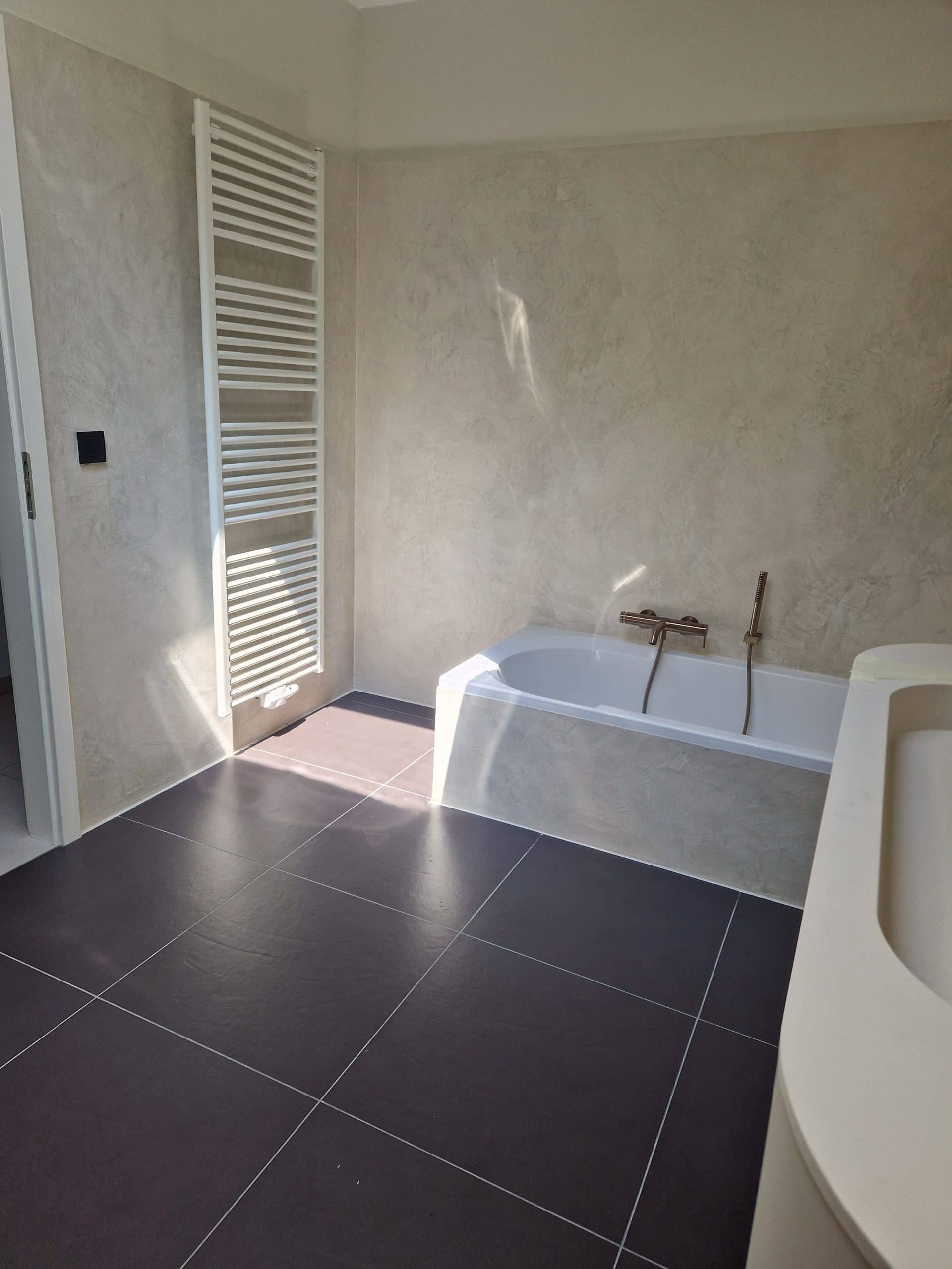 Salle de bain avec murs et tablier de baignoire en Mortex beige gris, carrelage anthracite au sol, réalisation Sol Color