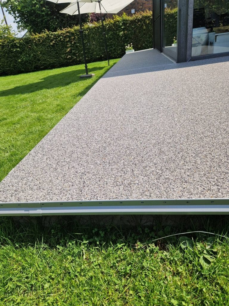 Terrasse en tapis de pierres gris clair le long d’une baie vitrée, réalisation Sol Color à Eupen