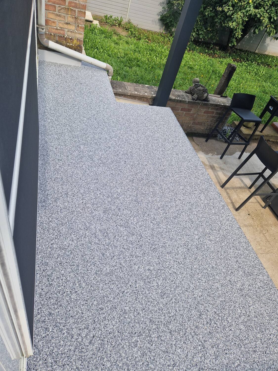 Terrasse grise en tapis de pierres attenante au jardin, réalisation Sol Color